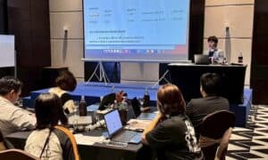 SEO-Friendly ALT Text: Business presentation on digital marketing strategies with multiple attendees using laptops in a modern conference room.